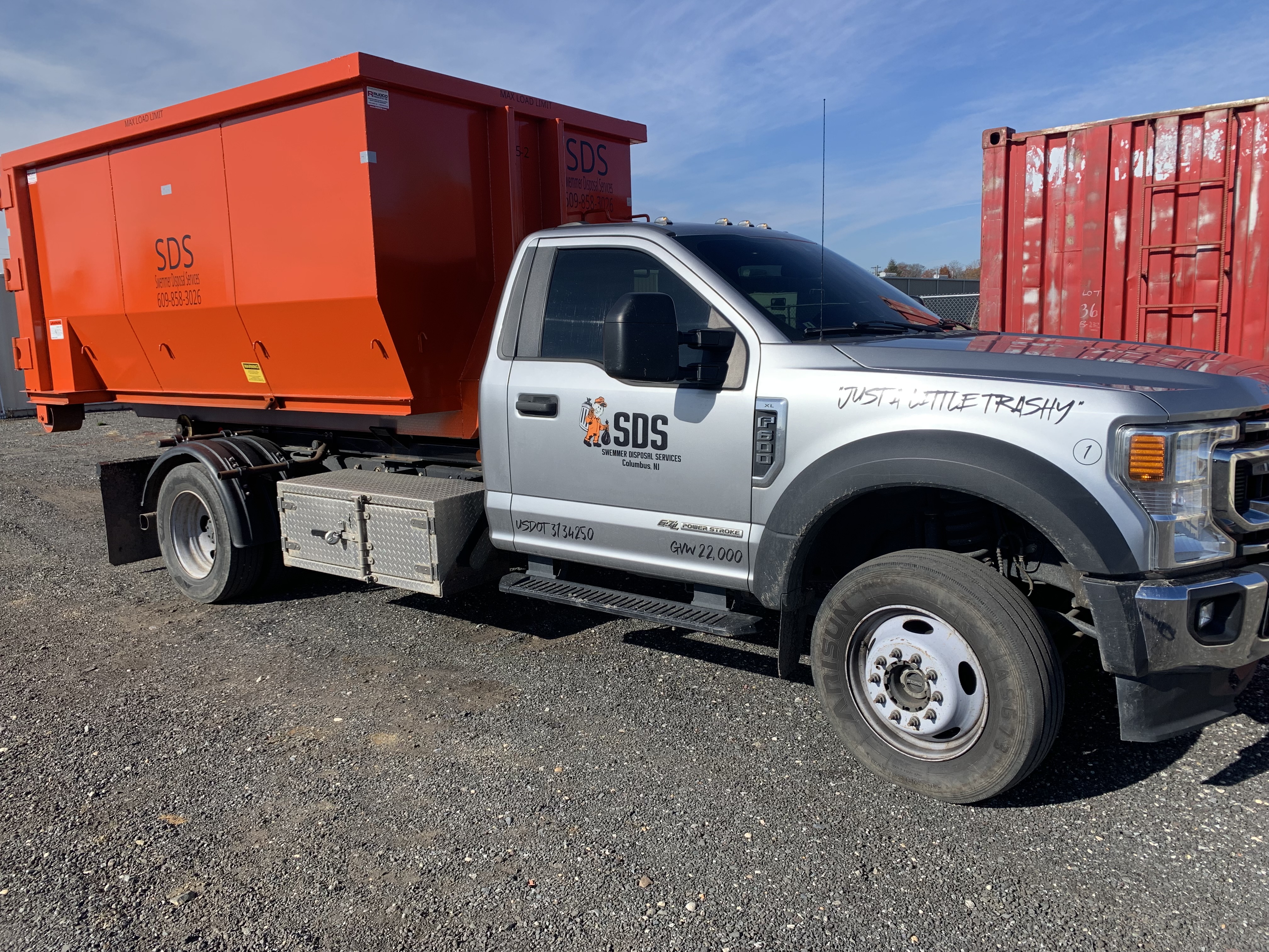 SDS roll-off truck loaded with an orange dumpster